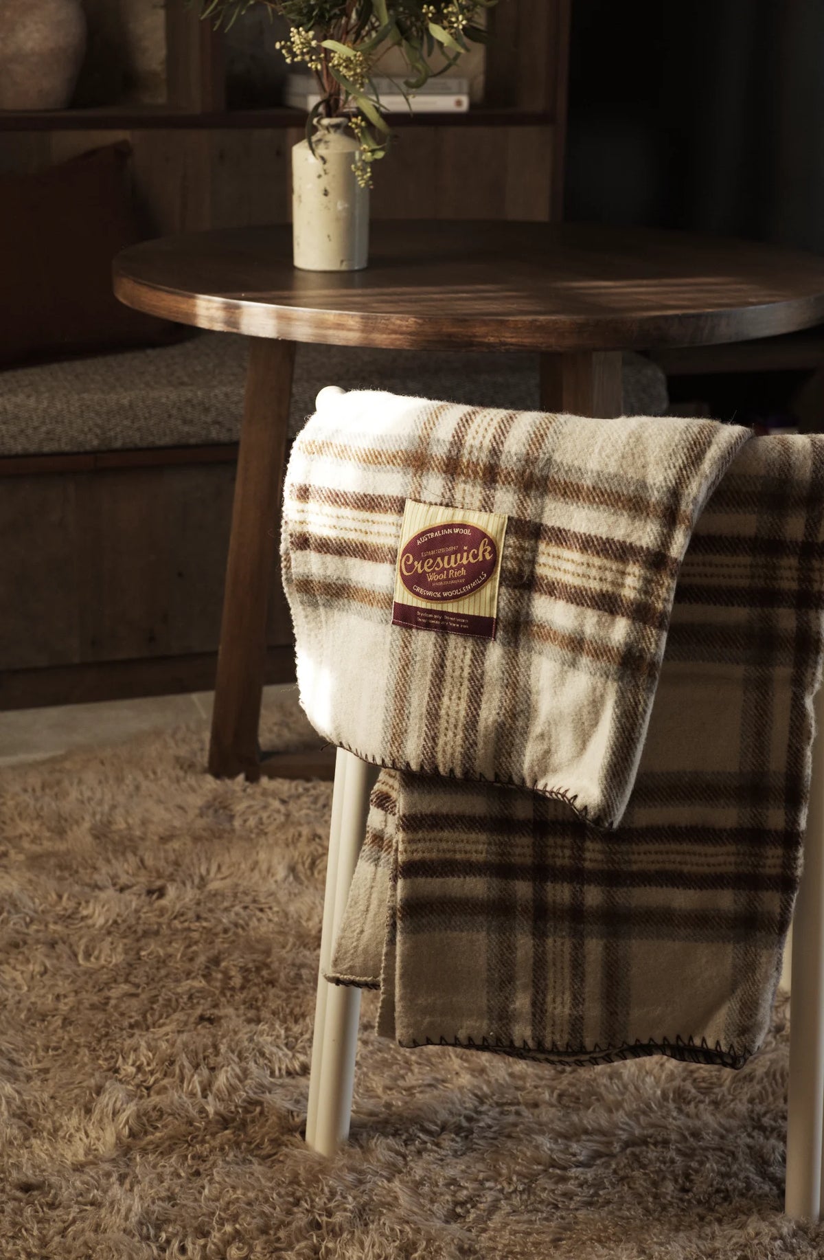 Creswick Wool blanket hung over a chair with a wool rug